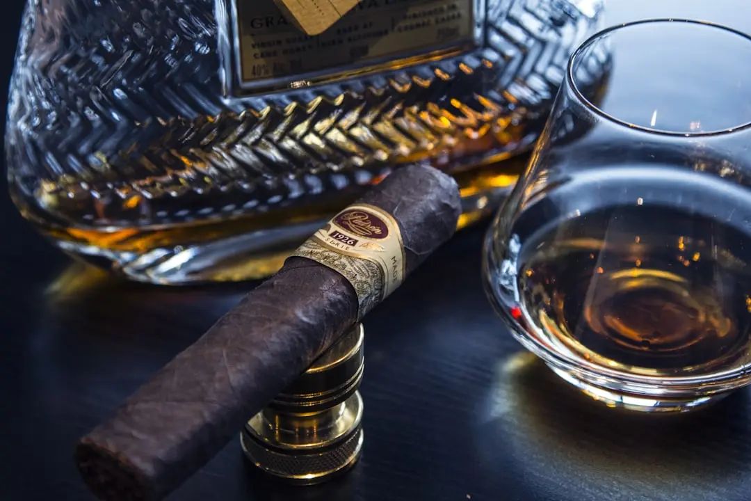 Glass of bourbon next to a cigar