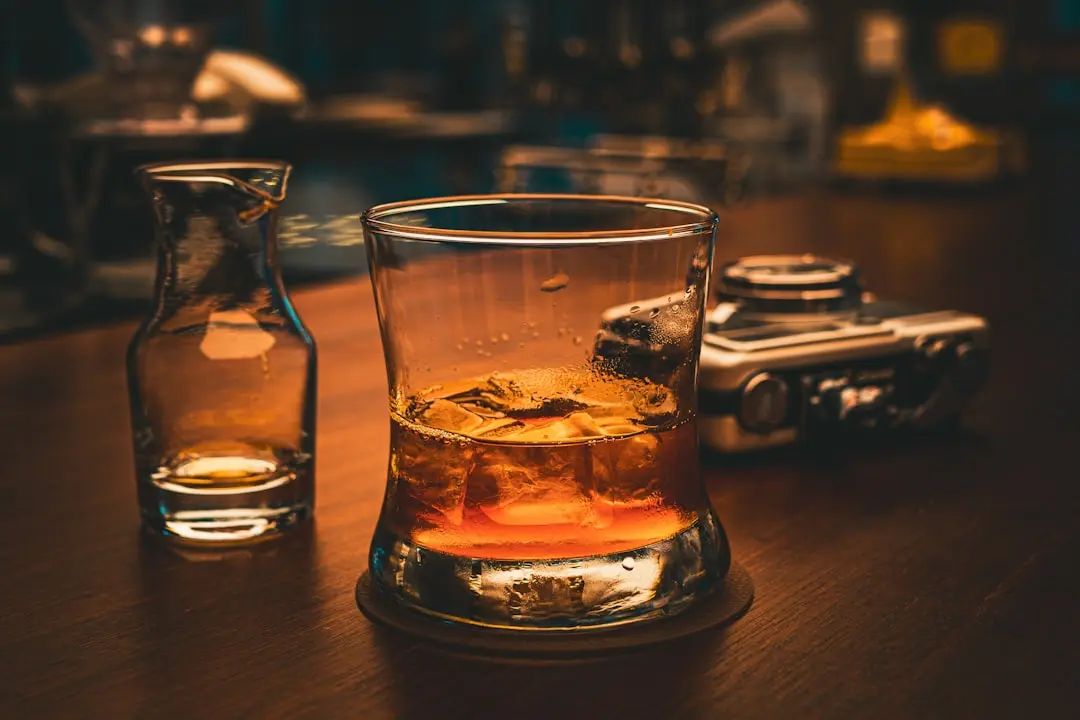 Glass of brandy with ice on a dimly lit table