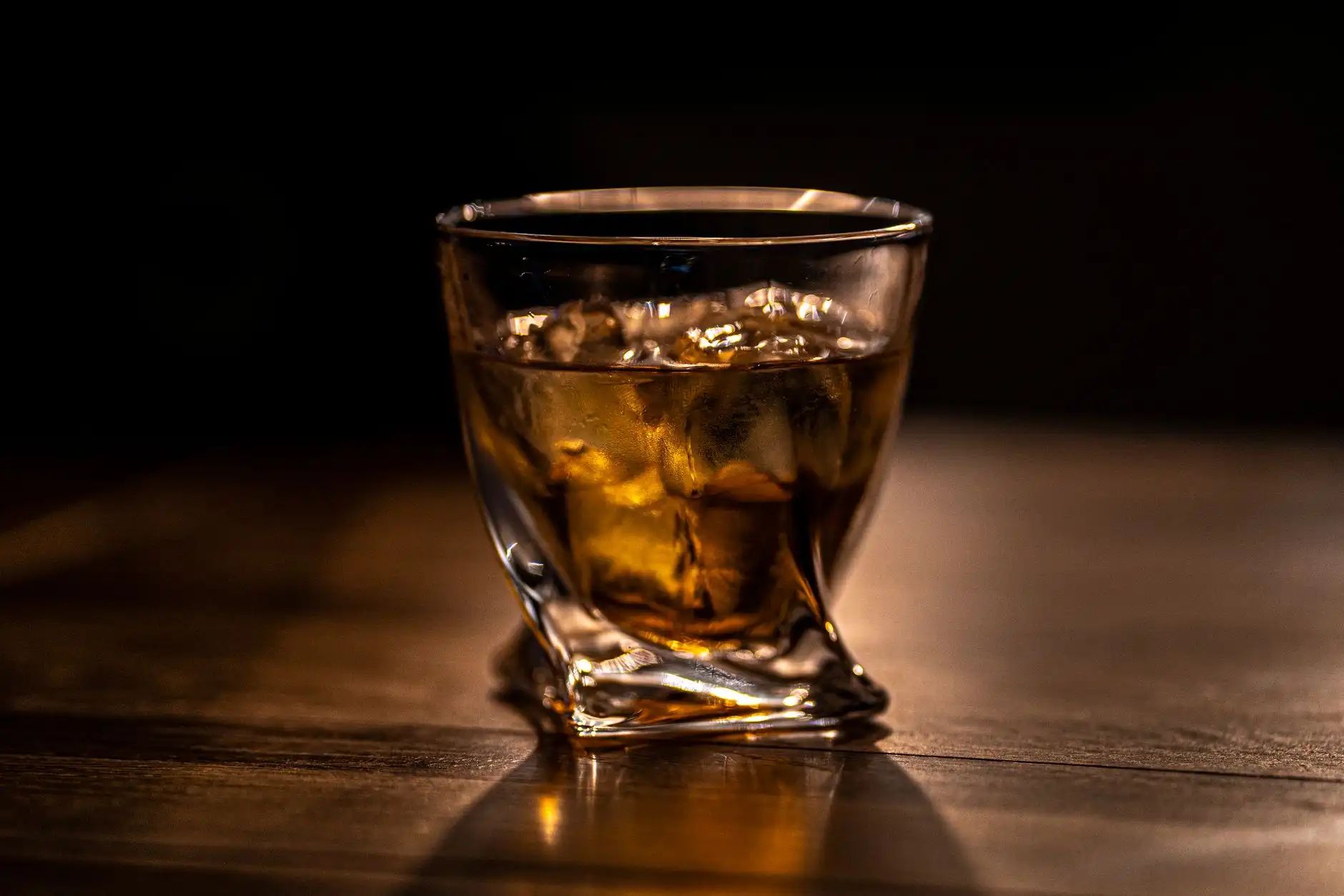Glass of Scotch whisky on ice on a wooden bar