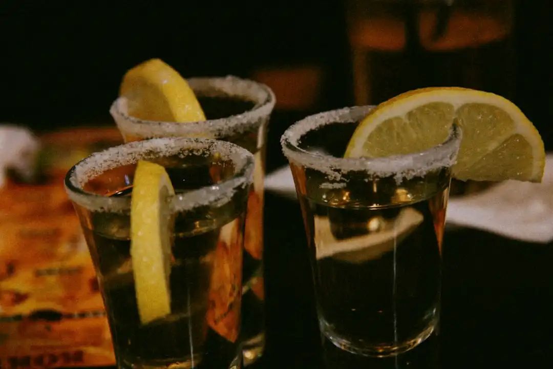 Salt-rimmed tequila shots with lemon wedges